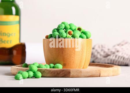 Bowl with wasabi coated crunchy peanuts on light background Stock Photo