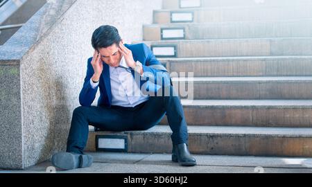 Sad businessman sitting on steps outside office. Stock Photo