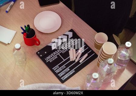 Moscow, Russia - October 04, 2025 - A creative workspace featuring essential filmmaking tools, including a clapperboard, pens, cups, and water bottles Stock Photo