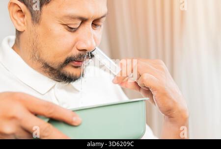 Close up portrait Asian man washes out the nose with saline, Treatment and prevention of the common cold and sinus. Treatment and healthcare concept Stock Photo