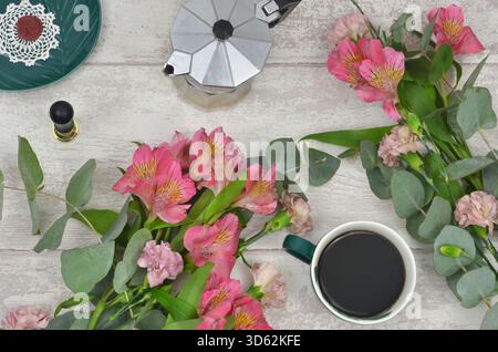 Black coffee (americano) and pink flowers, top view light wooden table. Stock Photo