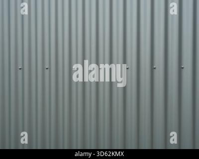 Vertical gray corrugated metal panels with rivets. Matte light and shadow play. Industrial aesthetic. Copyspace. Stock Photo