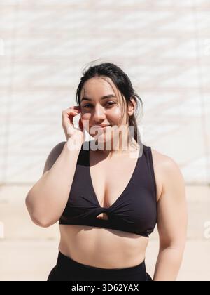 Natural portrait of a young woman with straight black hair, happy, looking at the camera, after a sports and exercise session outdoors Stock Photo