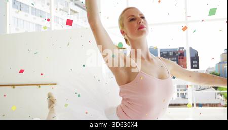 Posing dancer lifting arms raising leg en pointe in dance studio, leotard, tutu, barre, confetti Stock Photo