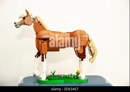 A detailed LEGO horse sculpture built from brown and tan plastic bricks, standing on a small green base Stock Photo