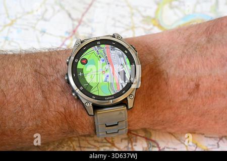 A Garmin Fenix 8 smartwatch worn on a wrist and displaying a detailed GPS map. The background shows a printed map emphasising the watch's navigation Stock Photo