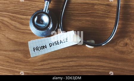 Stethoscope and Note Reading "Prion Disease" on Wooden Desk for Medical Research Stock Photo