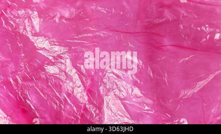 Bright Magenta Pink Crumpled Plastic Bag Texture with Wrinkles and Light Reflections Stock Photo