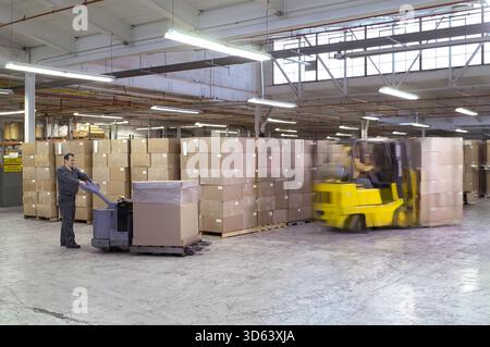 Warehouse workers moving boxes in distribution center. Stock Photo