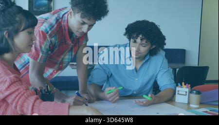 Working 3 students leaning over meeting table, woman in pink sweater, man holding green highlighter Stock Photo