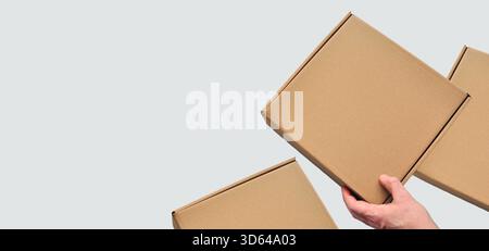 Paper box in hands, no notes. Sustainable packaging, shopping and packaging. Brown cardboard, square box, human hand, isolated Stock Photo