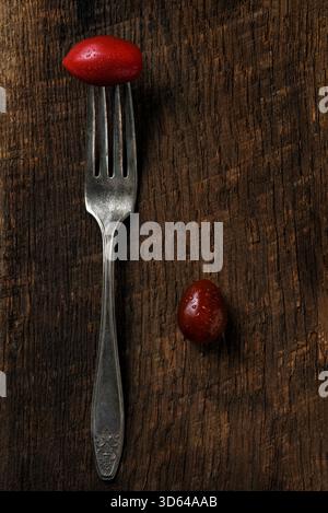 Tomato on the end of a fork on a rustic wood surface. Stock Photo