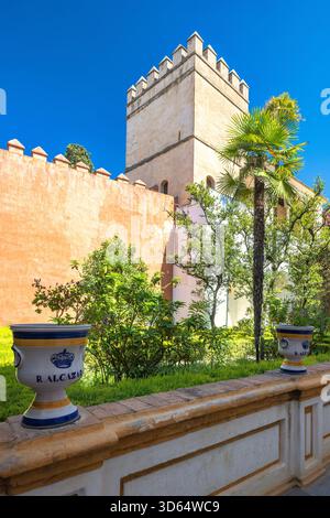 Seville, Spain - September 8, 2024: The Alcazar of Seville, historic royal palace. Ornate tower and tranquil garden within a historic walled complex. Stock Photo