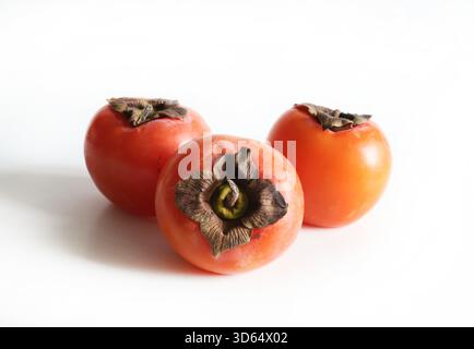 A group of ripe persimmons isolated on a white background. Diospyros kaki. Healthy autumn fruit. Overhead view. Stock Photo