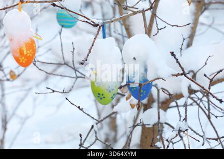 A tree branch covered in snow and decorated with Easter eggs Stock Photo