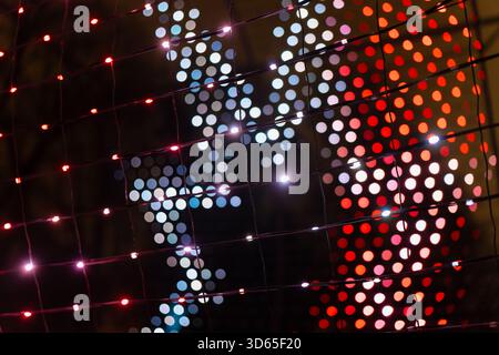 Night LED mesh featuring colorful red and white dotted sequences with cool blue highlights forming dynamic illuminated texture across grid surface ide Stock Photo