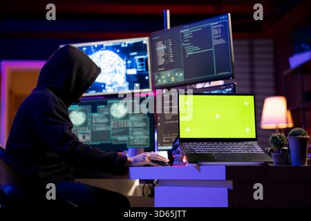 Hacker using isolated screen laptop to extract military secrets data from secure digital systems. Cybercriminal using mockup notebook device in hidden base, running espionage software Stock Photo