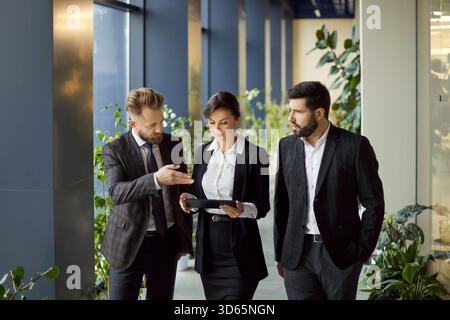 Business agents engages in focused discussion while walking through modern office corridor. Stock Photo