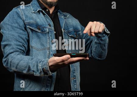 Close up to a man wearing a denim jacket pointing to a smartphone Stock Photo
