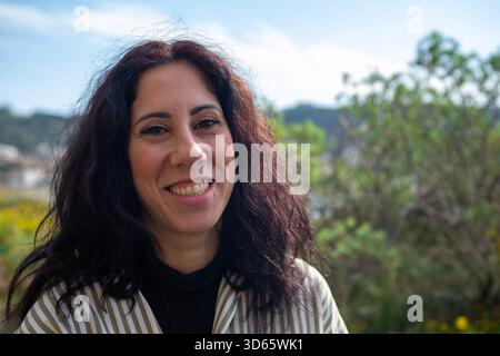 Close-up of happy woman against the backdrop of the Sicilian countryside. The woman is a thirty-nine year old brunette Stock Photo