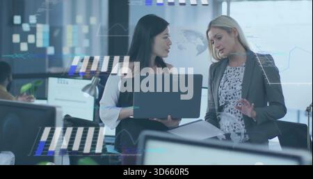 Working Asian woman holding laptop and manager in blazer gesturing papers in office, data overlays Stock Photo