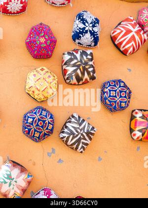 Beautiful patterned little hats on the yellow earthen wall Stock Photo