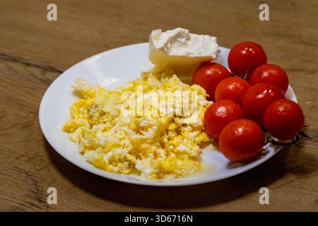 scrambled eggs with fresh cherry tomatoes on white plate Stock Photo