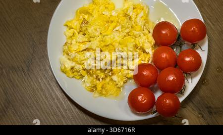 scrambled eggs with fresh cherry tomatoes on white plate  Stock Photo