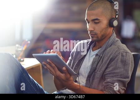 Gaming, headphones and tablet with developer man in office for software update or testing. App, playing and streaming with game designer in creative Stock Photo