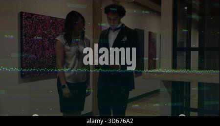Reviewing tablet, man in suit and woman in satin blouse skirt studying data overlay in gallery Stock Photo