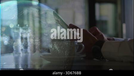 Tapping man's hands wearing long-sleeve shirt at cafe using phone, white cup, watch, planet overlay Stock Photo