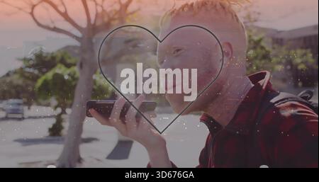 Talking man holding phone to mouth on sidewalk, red-black jacket and backpack with heart overlay Stock Photo