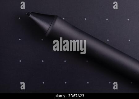 Close-up of a digital stylus on a dark background with dotted grid, ideal for creative, tech, and design concepts. Stock Photo