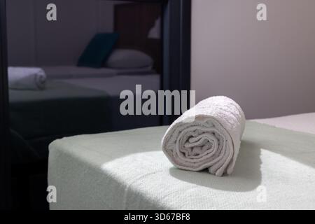 Clean rolled towel placed on mint blanket in modern guest bedroom interior Stock Photo