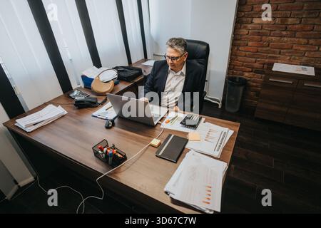 Professional office environment featuring a businessman working diligently on his laptop Stock Photo
