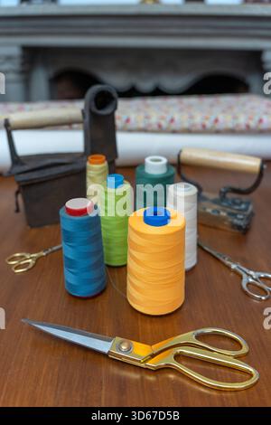 Crafting tools with colorful spools of thread and vintage irons on a wooden table Stock Photo