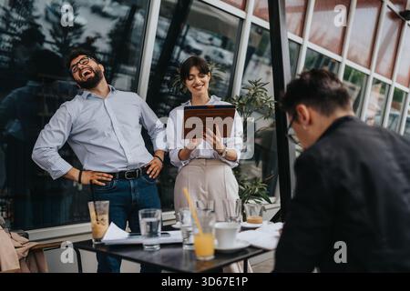 Group of co-workers laughing and collaborating outdoors during a meeting Stock Photo