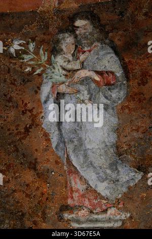Saint Anthony of Padua carries Christ Child while holding symbolic lily spray: worn 14th century fresco above chapel altar in unfinished Gothic Roman Catholic Cathédrale Saint-Pierre or Cathedral of Saint Peter at Beauvais, Oise, Hauts-de-France, northern France.  Lily symbolises Franciscan saint’s purity, holiness and lifelong struggle against the devil. Stock Photo
