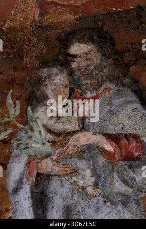 Saint Anthony of Padua carries Christ Child while holding symbolic lily spray: head to waist detail of flaking 14th century fresco above chapel altar in unfinished Gothic Roman Catholic Cathédrale Saint-Pierre or Cathedral of Saint Peter at Beauvais, Oise, Hauts-de-France, northern France.  Lily symbolises Franciscan saint’s purity, holiness and lifelong struggle against the devil. Stock Photo