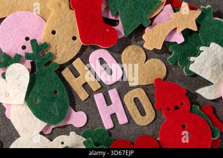 Colorful felt cutouts are spread on a dark surface, showcasing Christmas themes like reindeer, stockings, and snowmen. This scene is perfect for holid Stock Photo