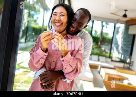 Joyful African-Asian couple embracing their diverse backgrounds, celebrating togetherness, identity Stock Photo