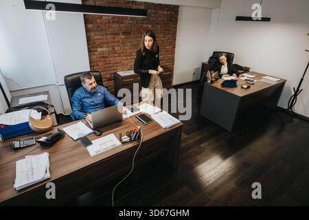 Three professionals collaborating in a modern office setting with documents Stock Photo