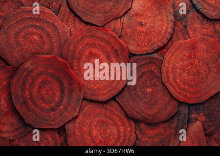 Organic red beetroot slices background. Fresh beetroot texture, close up, top view. Heap uncooked beet root cut into circular slices, dark burgundy co Stock Photo