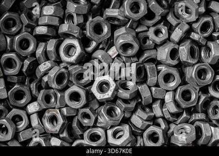 Many metal nuts on background. Chromed screw nuts, close up, top view. Steel nuts pattern. Tools for work. Black and white Stock Photo