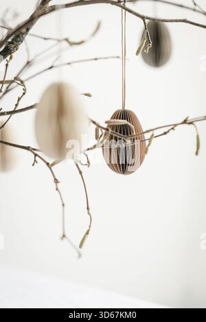 Easter paper eggs hanging on branches. Scandinavian-style Easter decorations. Stock Photo