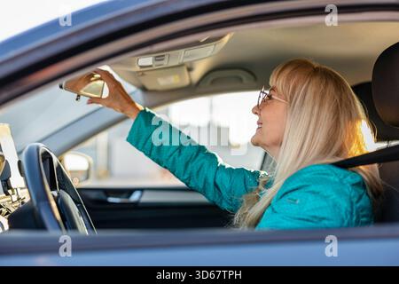 Side view of a mature woman looking in the rearview mirror while driving Stock Photo