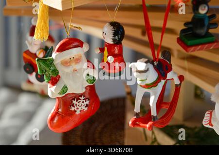 Christmas decorations featuring Father Christmas and other wooden figurines, hung from a homemade fir tree branch made from wooden planks Stock Photo