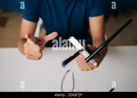 Close-up of technician hands assembling wi-fi module on white table, using small screwdriver and other components for computer upgrade or repair. Stock Photo