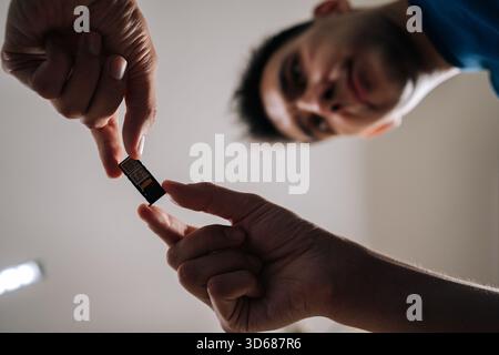 Shooting from below of young man replacing sim card in mobile phone, providing efficient and reliable technical support to customer. Stock Photo