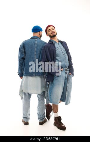 Two brothers stand back to back, exuding confidence in their trendy denim outfits. Stock Photo